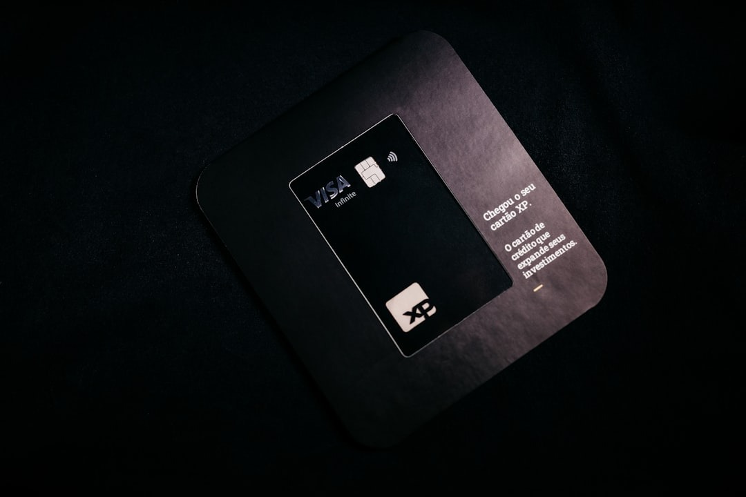Black credit card in a matching grey holder on textured surface.